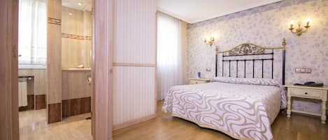 Un dormitorio con cama, mesitas de noche, tocador y armario.