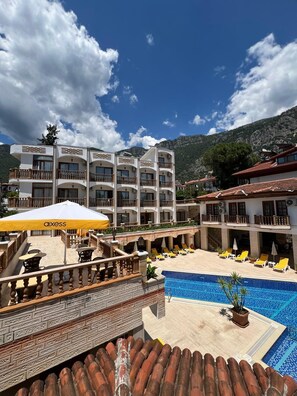 A hotel with multiple balconies, a swimming pool, and outdoor seating.