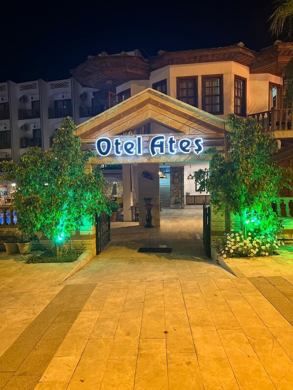 The entrance to a hotel with a sign reading 'Hotel Ates' and a tiled pathway leading to the entrance.