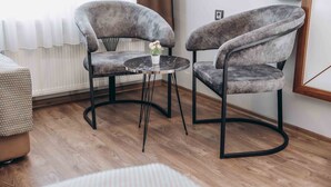 A room with two grey upholstered chairs around a small round table with a vase of flowers. - Hakcan Hotel (Izmir)
