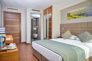 A hotel room with a bed, bedside table, and a painting on the wall. - Hakcan Hotel (Izmir)