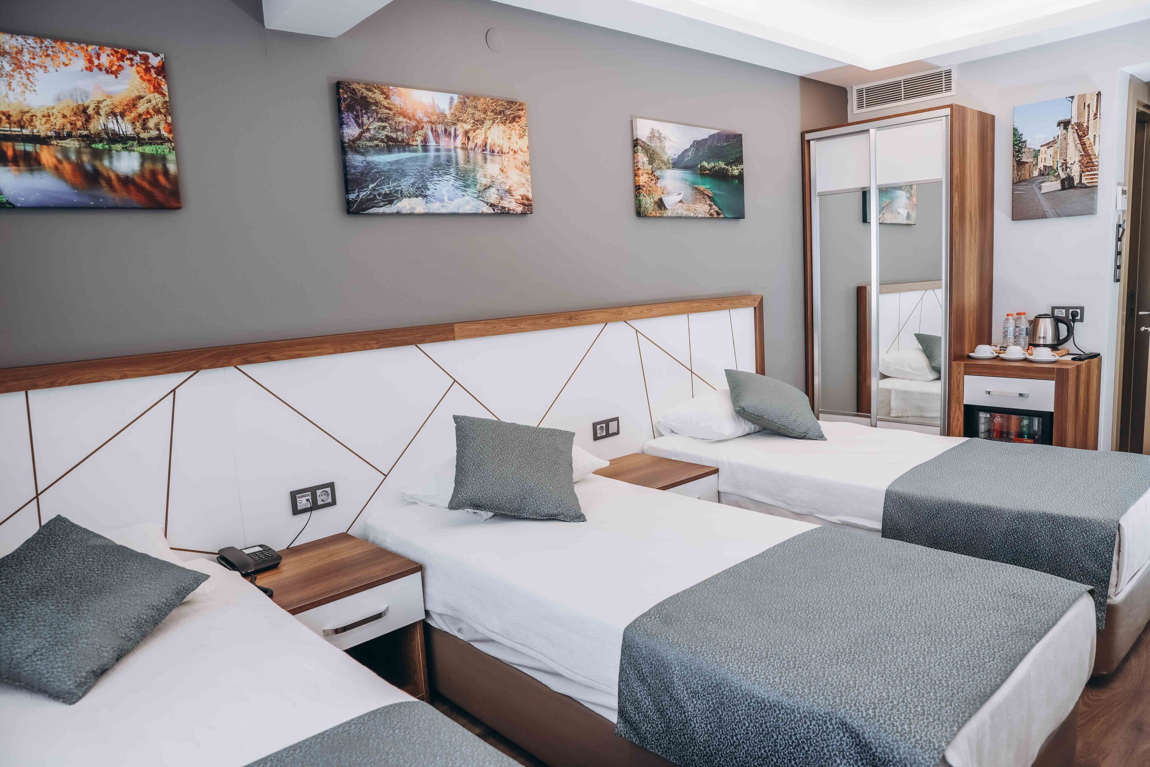 A hotel room with two single beds, a wooden headboard, a bedside table with a phone, and a small table with a coffee maker.