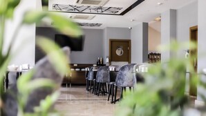 A restaurant with a long counter, multiple chairs, and a ceiling with a geometric design. - Hakcan Hotel (Izmir)