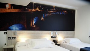 A hotel room with two beds, a nightstand, a small table, and a wall-mounted phone. - Hostal Don Suero de Quiñones (Hospital de Orbigo)