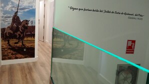 A hallway with a mural of a horse and rider, a glass display case, and a sign with text. - Hostal Don Suero de Quiñones (Hospital de Orbigo)