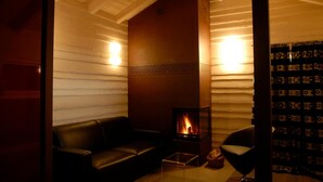 A cozy room with a fireplace, leather sofa, and a glass coffee table. - Chalet nel Doch (Primiero San Martino di Castrozza)