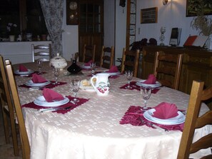 A dining table set with plates, glasses, and a pitcher, surrounded by wooden chairs. - L'hirondelle (Girondelle)