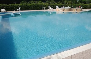 A clear swimming pool with lounge chairs and a stone structure. - Il Venticello Agriturismo (Santa Cesarea Terme)