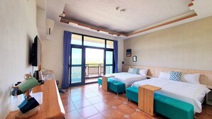 A hotel room with two beds, a desk, and a balcony with a view. - Warm & Cozy Inn (Hengchun)