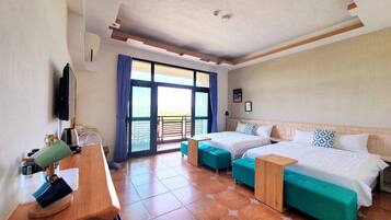 A hotel room with two beds, a desk, and a balcony with a view.