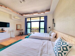 Une chambre d’hôtel avec deux lits, une télévision, un bureau et un balcon avec vue.