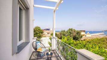 A balcony with a chair, a small table, and a potted plant.