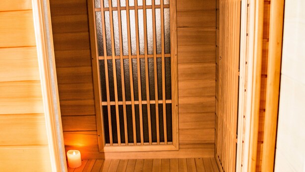 Eine Holzsauna mit einer Latertür und einer brennenden Kerze auf dem Boden.