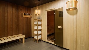 Habitación con detalles de madera, un banco, una estantería con toallas y la puerta de una sauna.