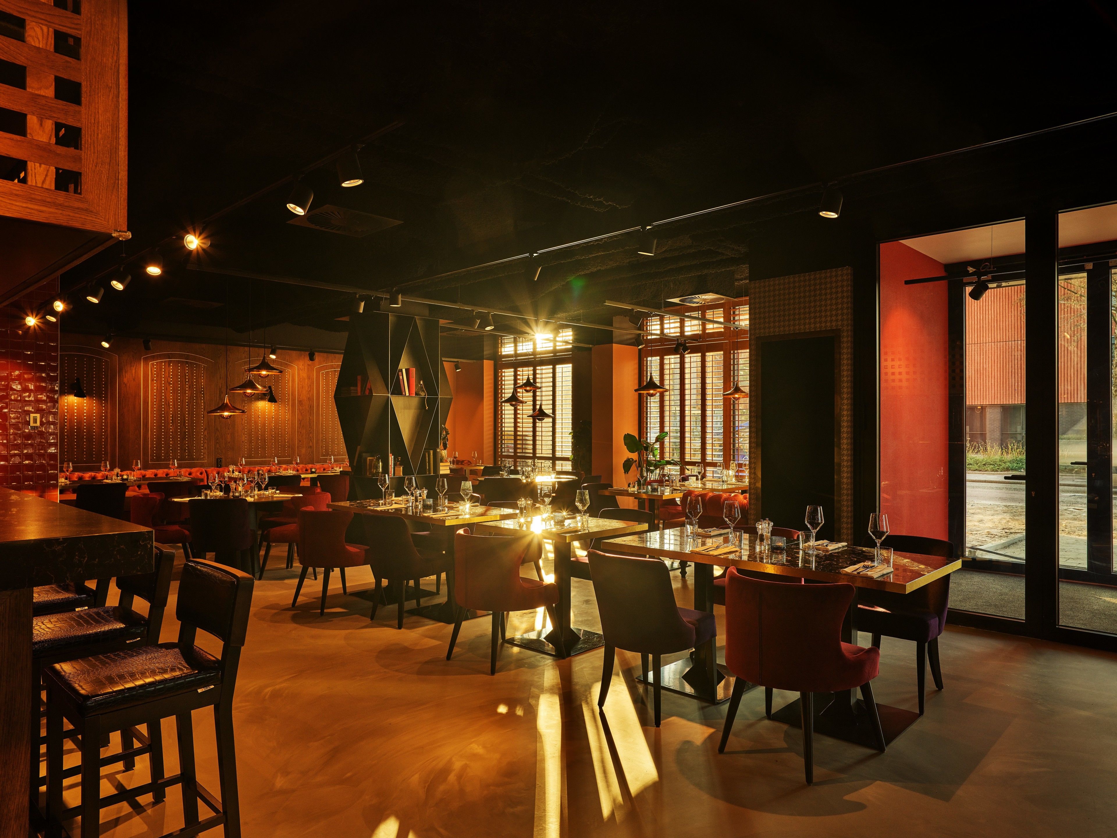 A restaurant interior with tables set for dining, a bar area, and large windows providing natural light.