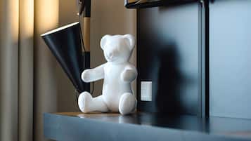 Una figurita de oso blanco de cerámica sobre una estantería, junto a una lámpara negra.