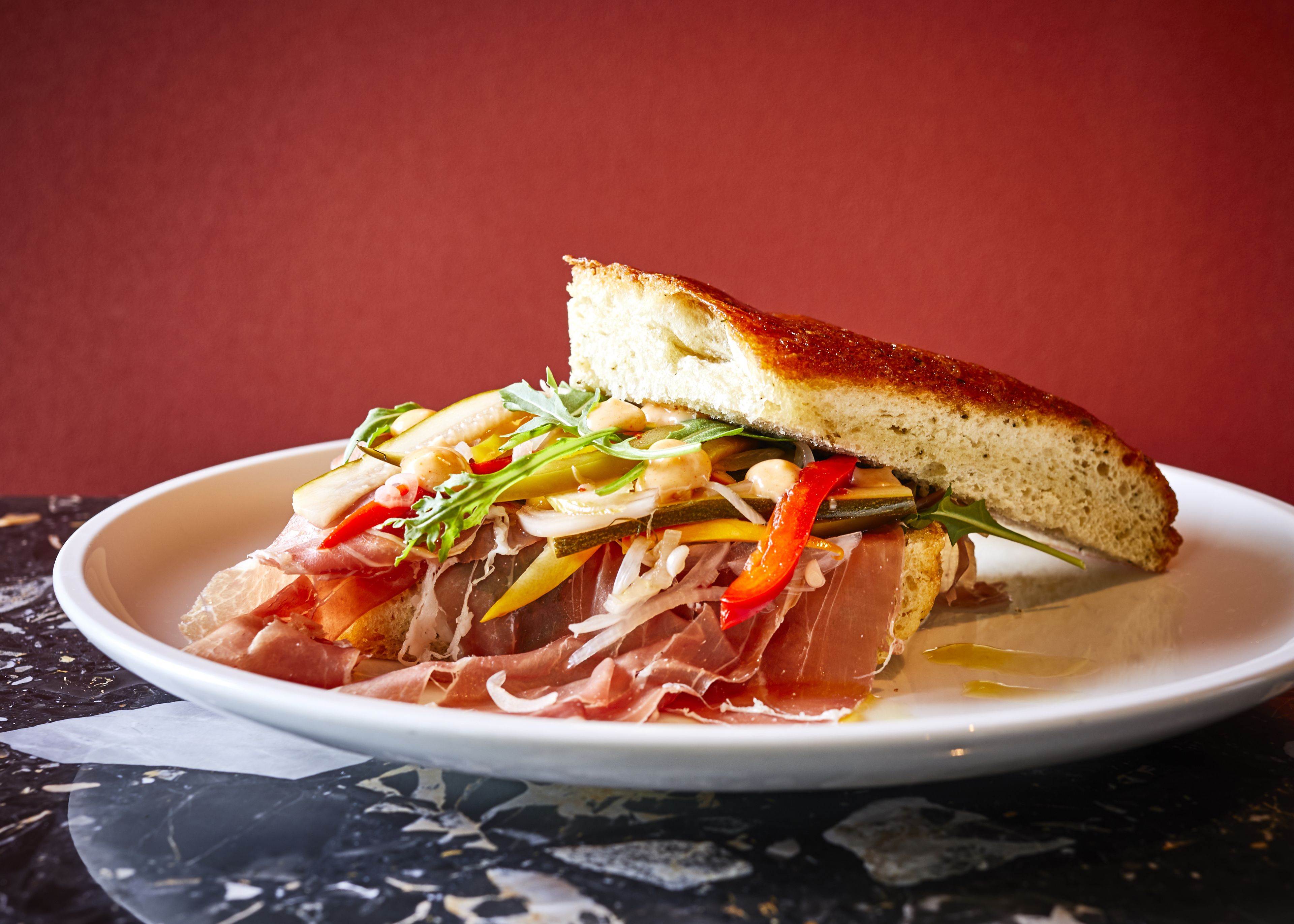 A sandwich with various ingredients on a white plate.