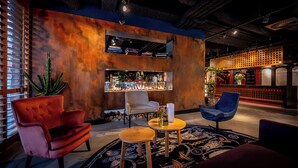 Zona de bar moderna con chimenea, asientos y barra.
