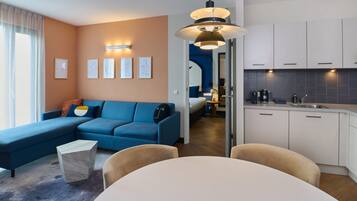 Een moderne woonkamer met een blauwe bank, een marmeren salontafel en een eethoek met een witte tafel en stoelen.