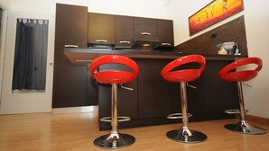 Eine moderne Küche mit dunklen Schränken, einer Edelstahl-Dunstabzugshaube und einer roten Bar mit Sitzplätzen.