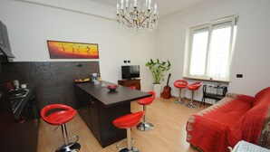 Eine moderne Küche mit Essbereich, einem roten Sofa und einem großen Fenster.