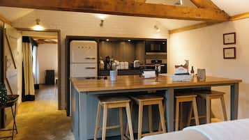 A kitchen with wooden beams, a large island with stools, a refrigerator, and a microwave.