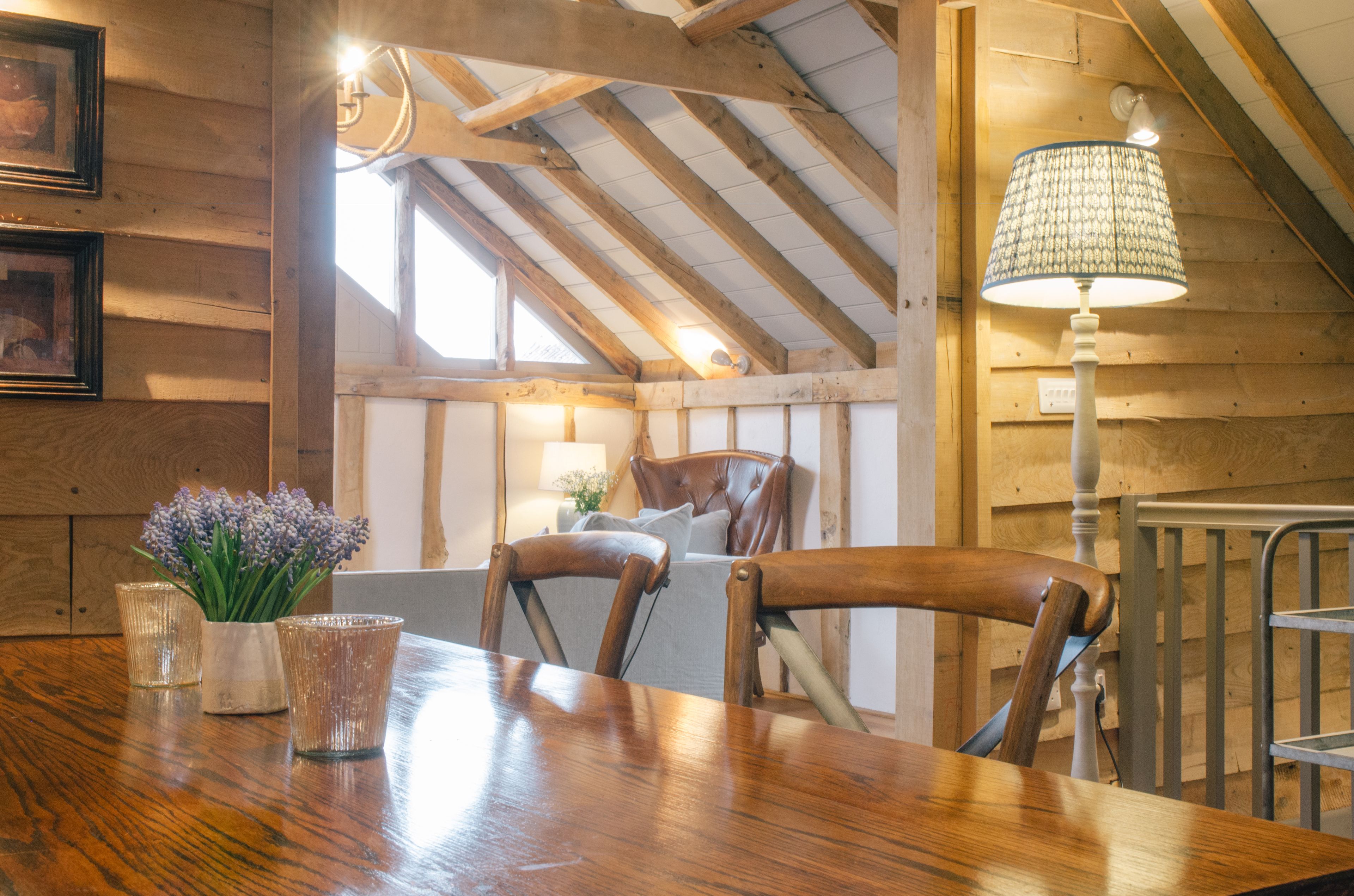 Un tavolo da pranzo in legno con sedie, una lampada e un vaso con fiori.