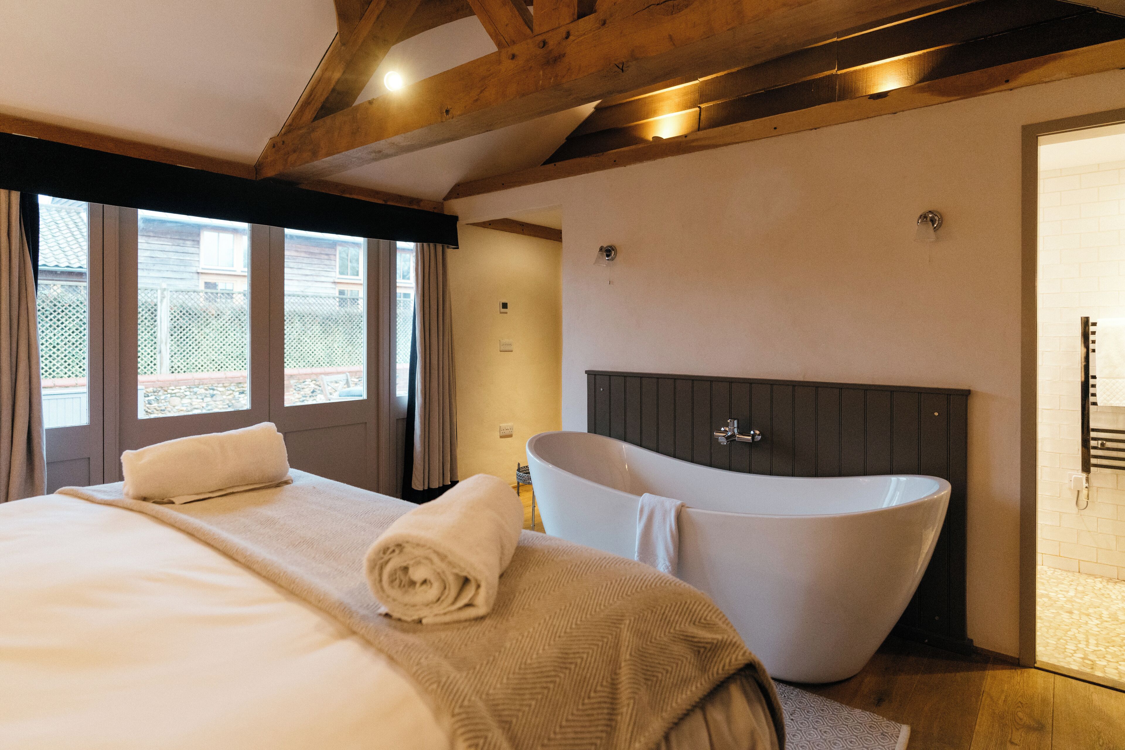 Un dormitorio con una cama grande, una bañera y vistas al exterior.