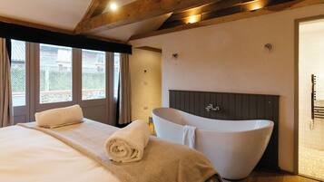 Un dormitorio con una cama grande, una bañera y vistas al exterior.