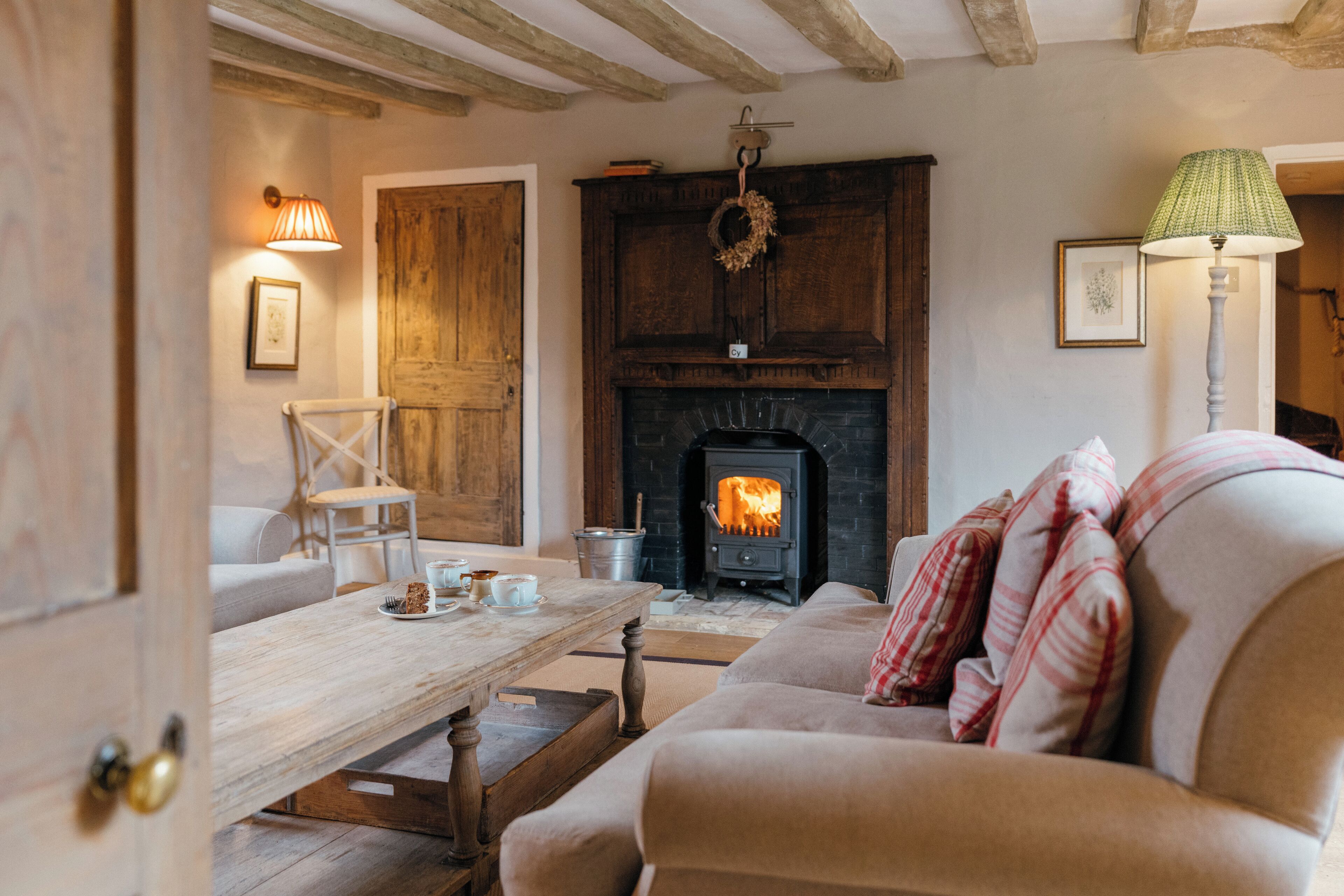 A cozy living room with a fireplace, wooden furniture, and a table with cups and a plate.