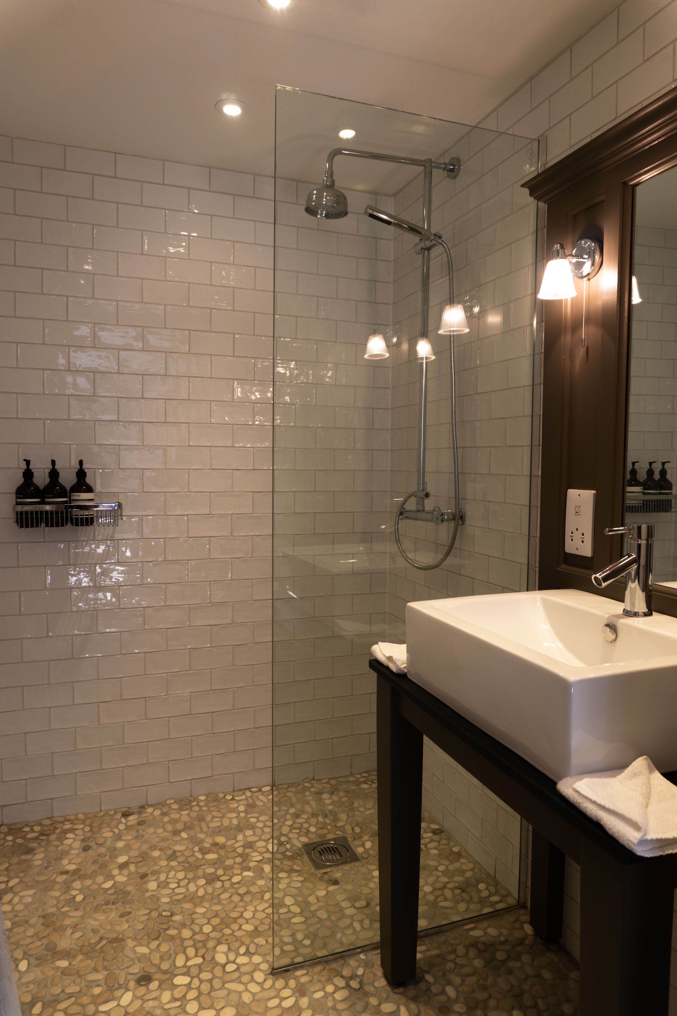 A modern bathroom with a glass-enclosed shower, a white sink, and a mirror.