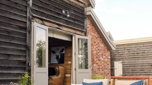 A cozy outdoor seating area with wooden furniture and a table set with wine glasses and bottles. - Retreat East (Ipswich)