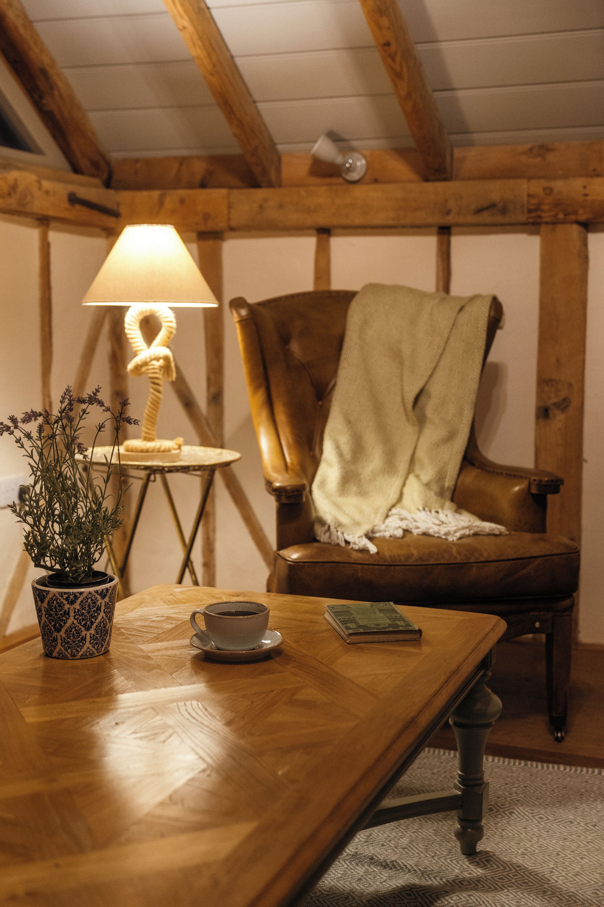 Une table en bois avec une tasse, un livre et une plante en pot.