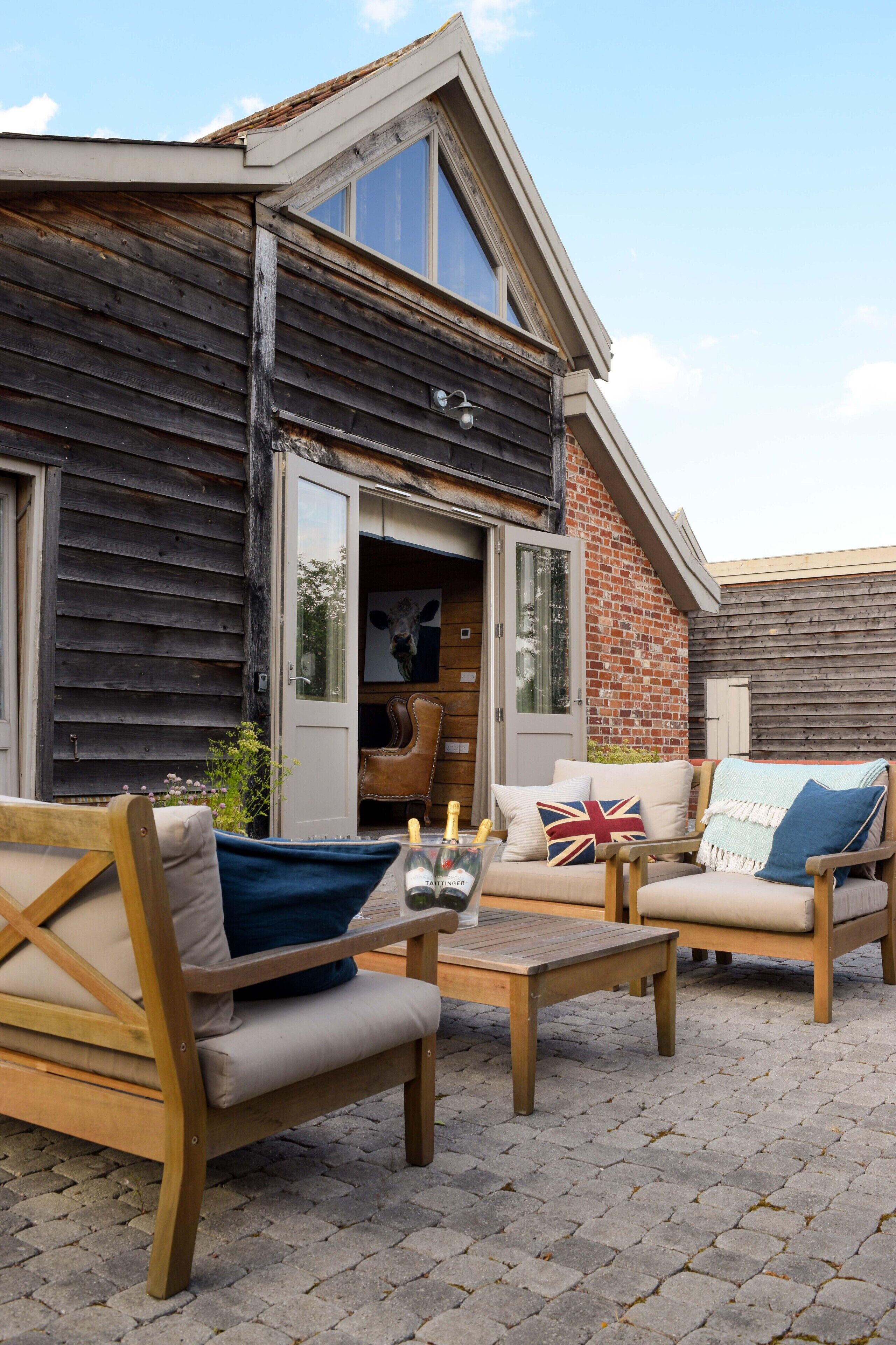 A rustic outdoor seating area with wooden furniture and a brick wall.