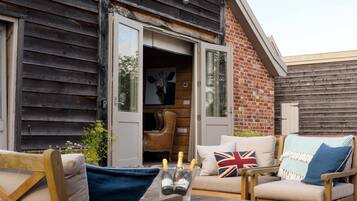 A rustic outdoor seating area with wooden furniture and a brick wall.