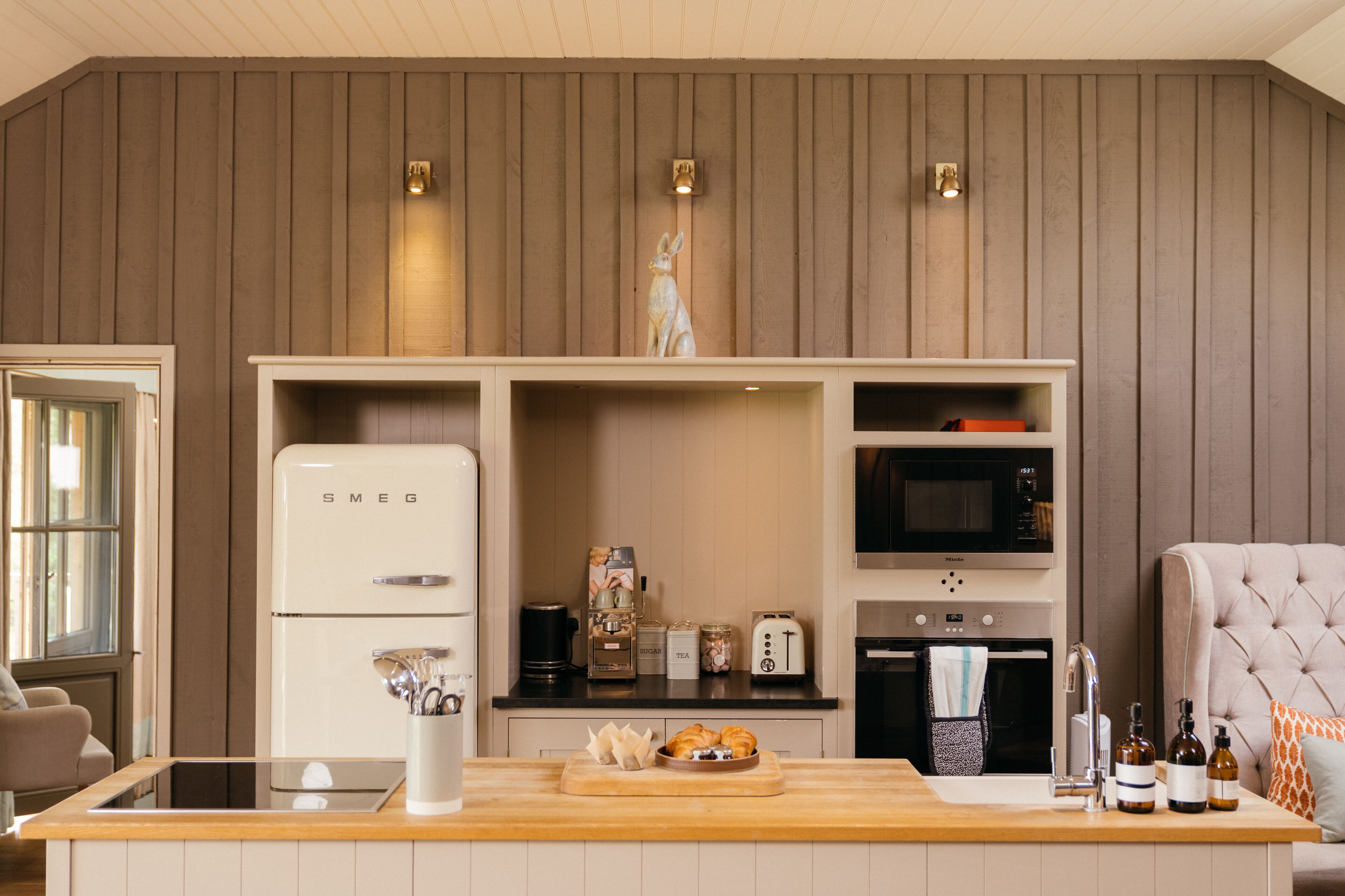 Una cocina compacta con un refrigerador blanco, un microondas, un tostador y una encimera de madera.