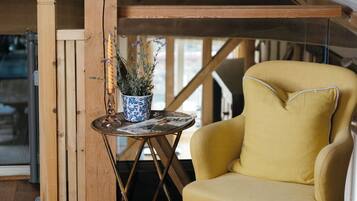 Een gele fauteuil in een houten kamer met een klein tafeltje en een potplant.