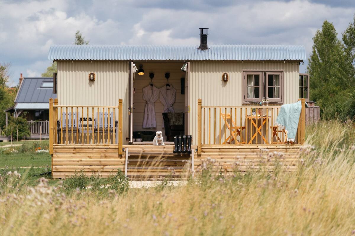 A wooden cabin with a porch, a small deck, and a covered entryway.