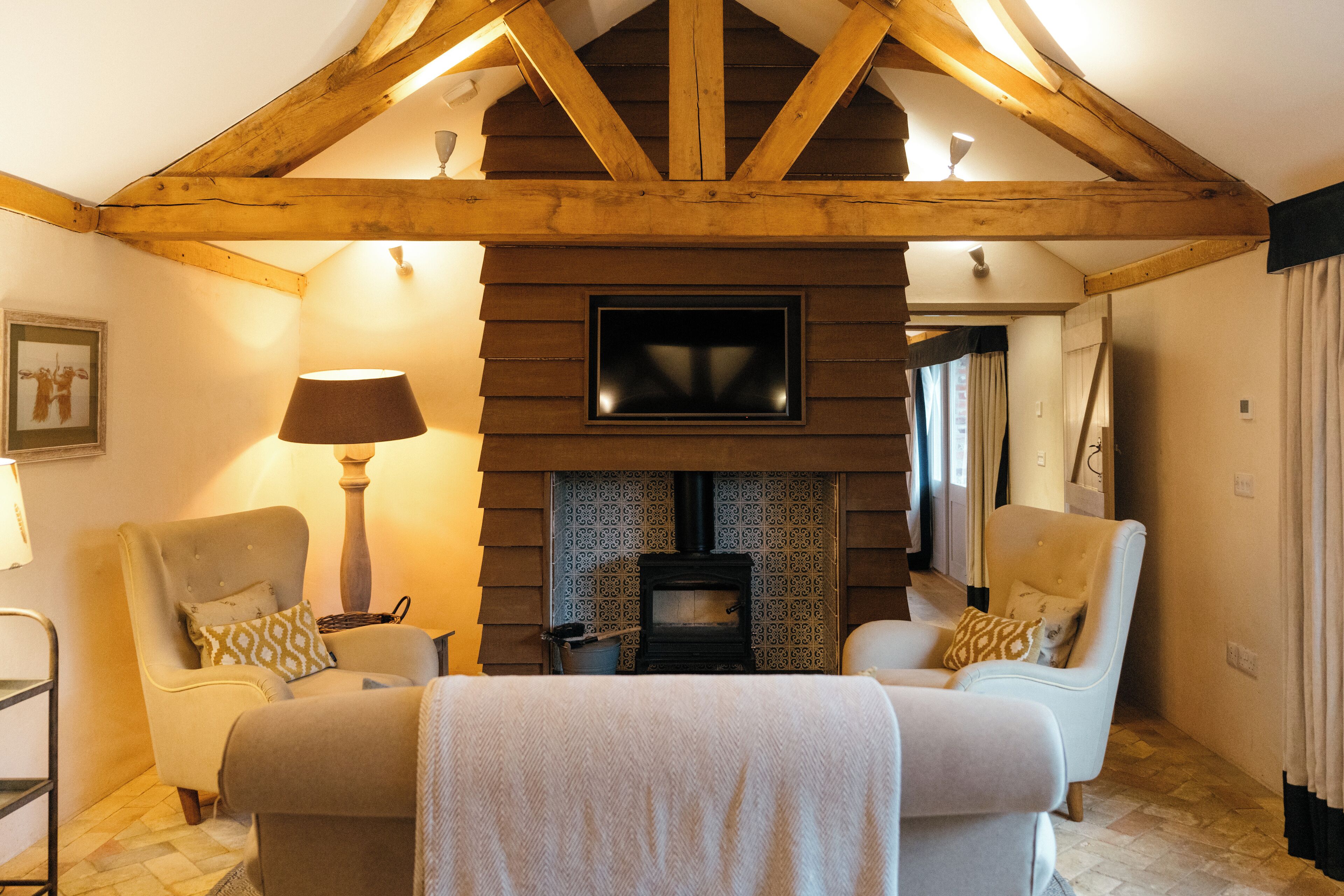 A cozy living room with two armchairs, a fireplace, and a television mounted on the wall.