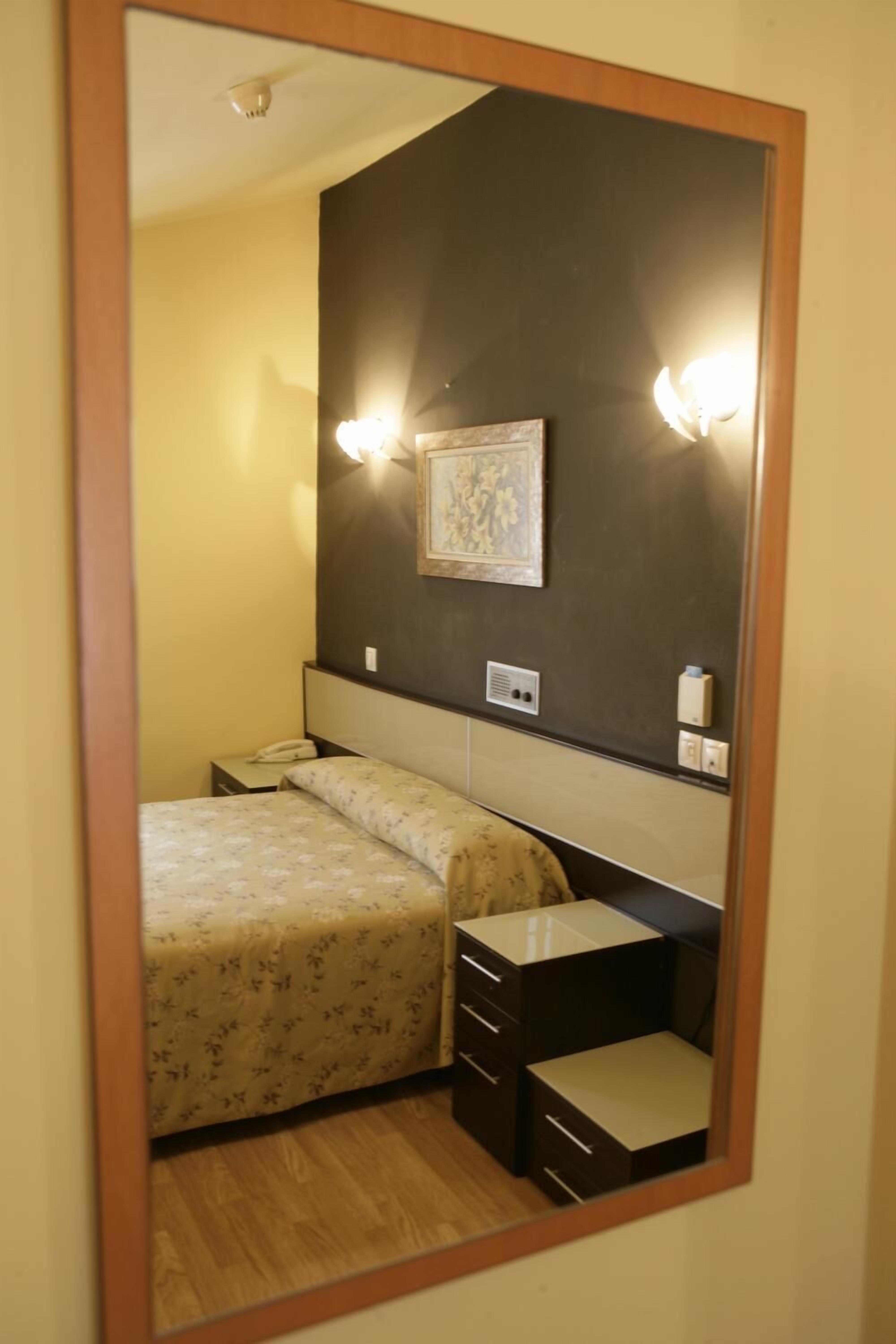 Un dormitorio con cama, mesita de noche y espejo.