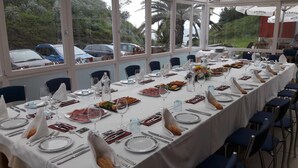 Una larga mesa de comedor lista para una comida, con platos, cubiertos y vasos.
