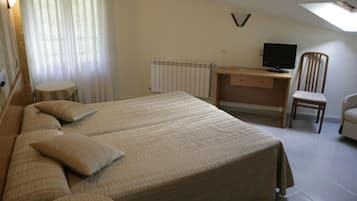 Un dormitorio con una cama grande, un escritorio, una silla, un radiador y un televisor.
