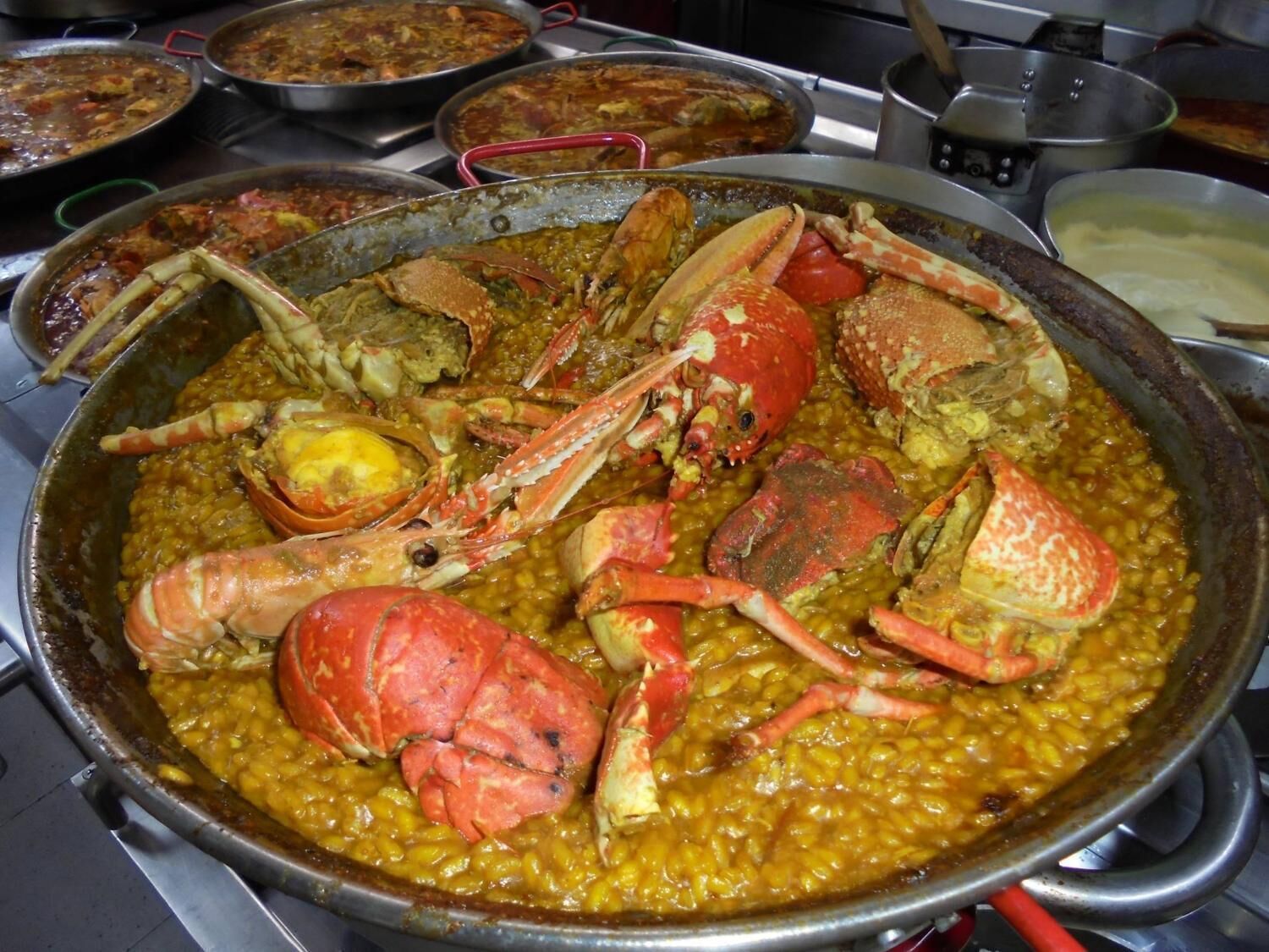 Una olla grande con guiso de mariscos, incluyendo cangrejos y maíz.