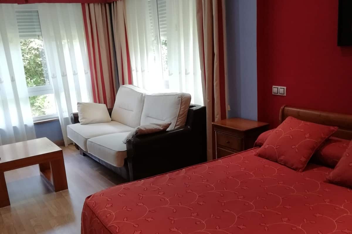 Ein Hotelzimmer mit einem großen Bett, einer Couch, einem kleinen Tisch und Vorhängen.