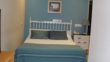 Une chambre à coucher avec un lit, une table de chevet, une lampe et un tableau encadré au mur.