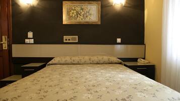 A hotel room with a bed, two bedside tables, a telephone, and a wall-mounted light fixture.