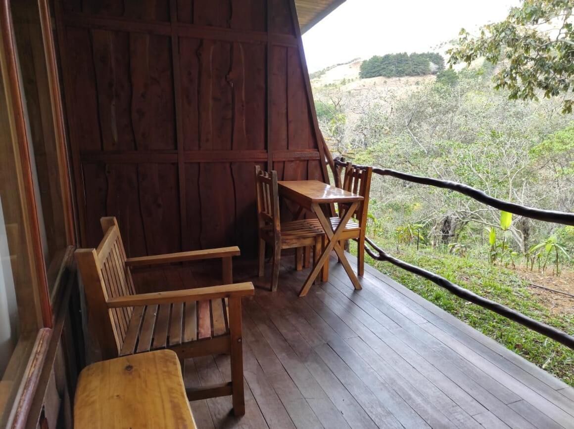 A wooden deck with a table and chairs, overlooking a natural landscape.