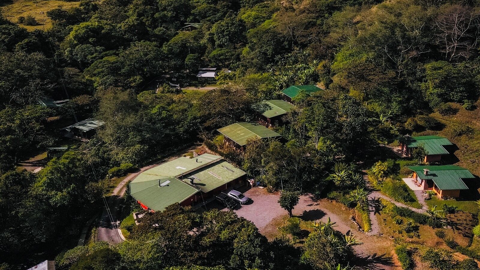 Vista aérea de um resort com vários edifícios rodeados por uma floresta densa.