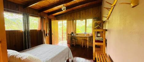 Un dormitorio de cabaña de madera con una cama, un escritorio y una litera.