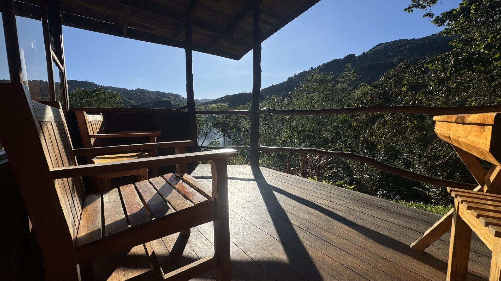 Un muelle de madera con bancos que da a un paisaje montañoso.